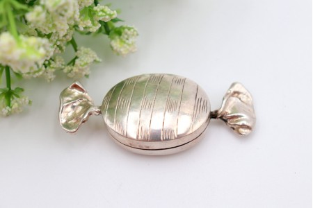 Caixa de comprimidos em prata em forma de rebuçado com relevos